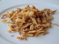 Crispy fried onions (birista) on a white plate